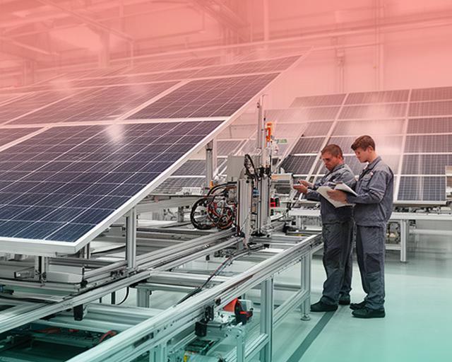 Interior de una planta de fabricación solar con paneles ensamblados y personal técnico en Camas